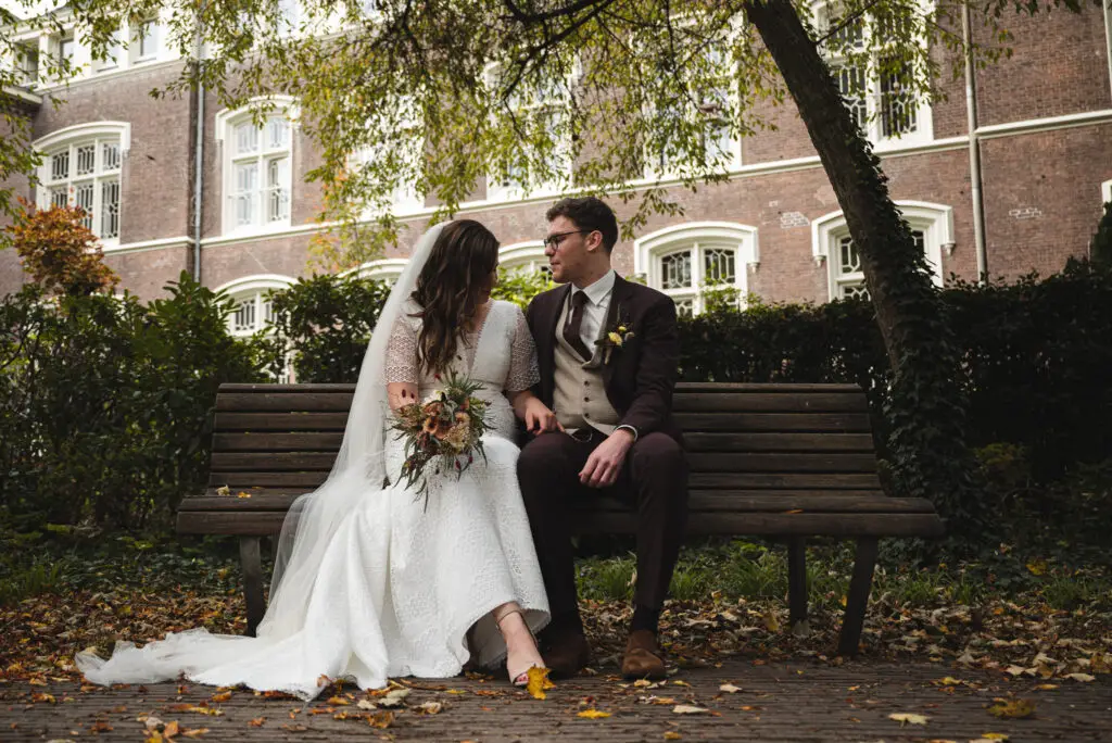 het bruidspaar rust even uit op een bankje tijdens de trouwfotoshoot